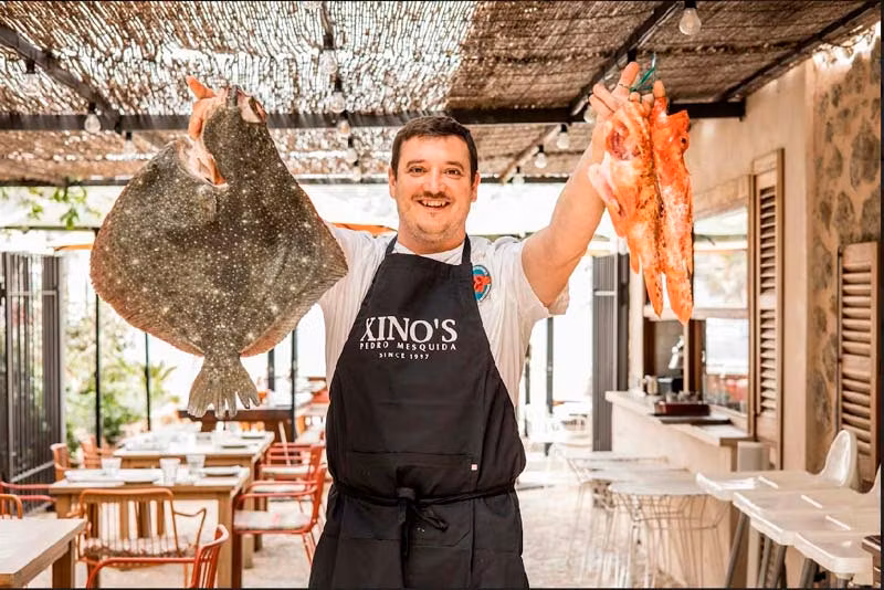 camarero sujetando pescados en Villa Luisa en Mallorca
